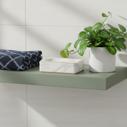 Marble-look soap dish with gold trim on a sage green bathroom shelf