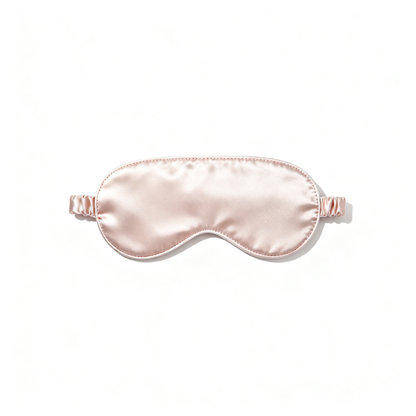 Blush-pink satin sleep mask with softly padded curved shape on a white background